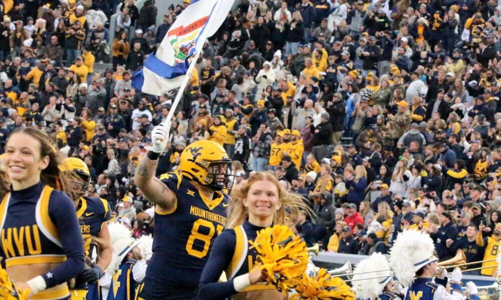 WVU Football TE Treylan Davis with WV flag and cheerleaders