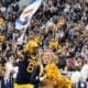 WVU Football TE Treylan Davis with WV flag and cheerleaders