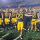 WVU Football players with Rodney Gallagher in front celebrating after beating Pitt in Backyard Brawl