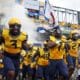 West Virginia football running with flag