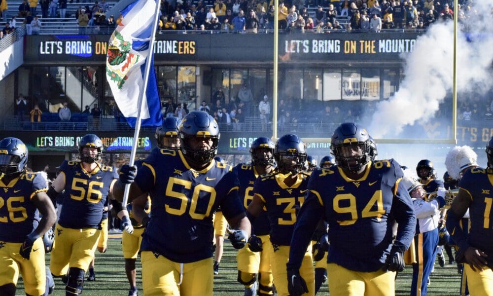 WVU Football team carrying flag