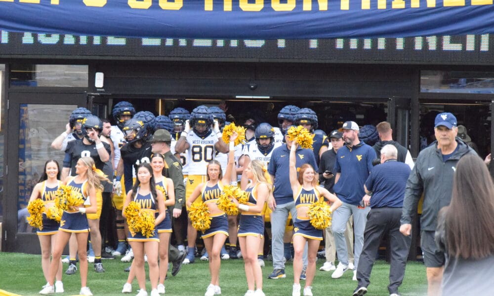 WVU Football team behind cheerleaders