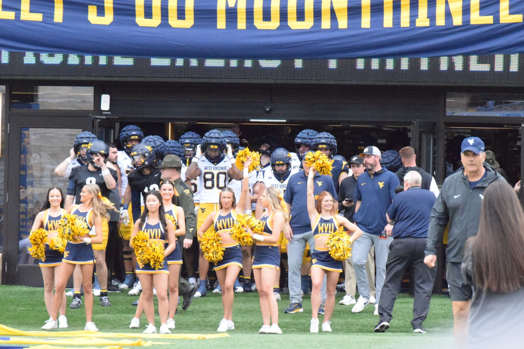 WVU Football team behind cheerleaders