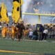 Mountaineer running on WVU Football field with flags