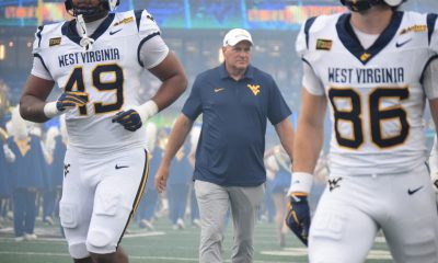 WVU Football HC Rich Rodriguez in between players