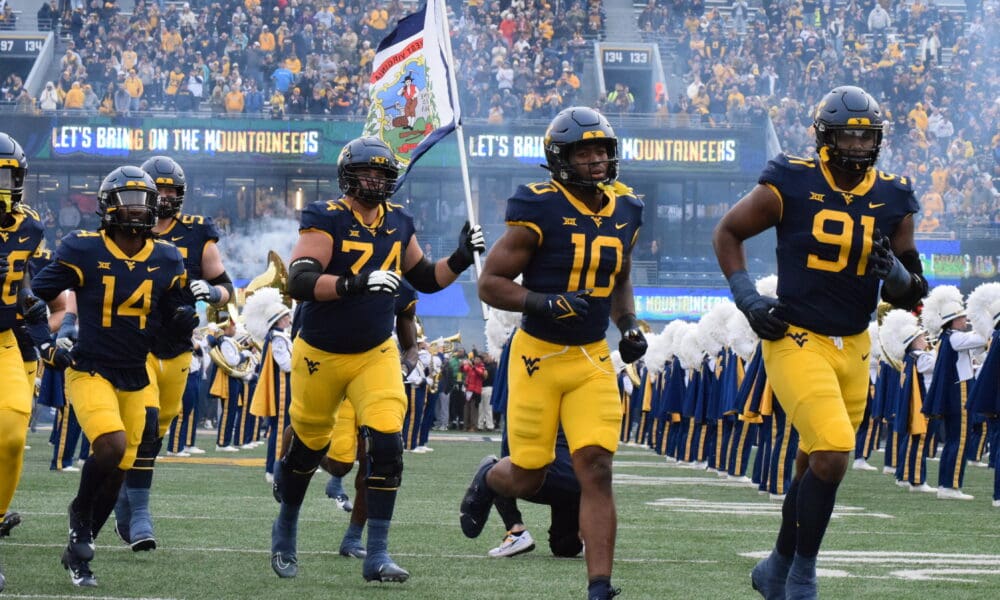 WVU Football players run on field with flag, including OL Wyatt Milum