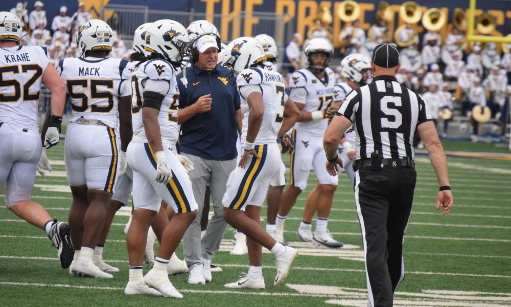 WVU Football HC Rich Rodriguez in huddle with players and Michael Hawkins