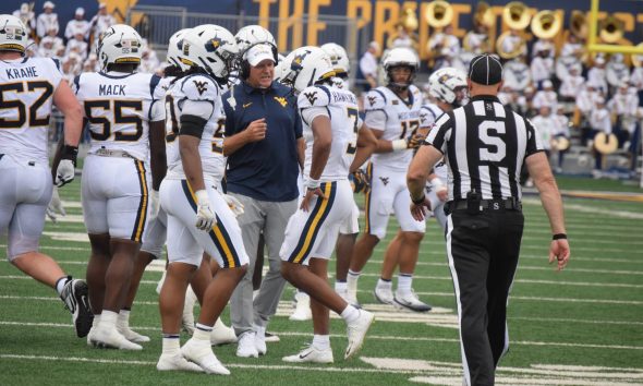 WVU Football HC Rich Rodriguez in huddle with players and Michael Hawkins