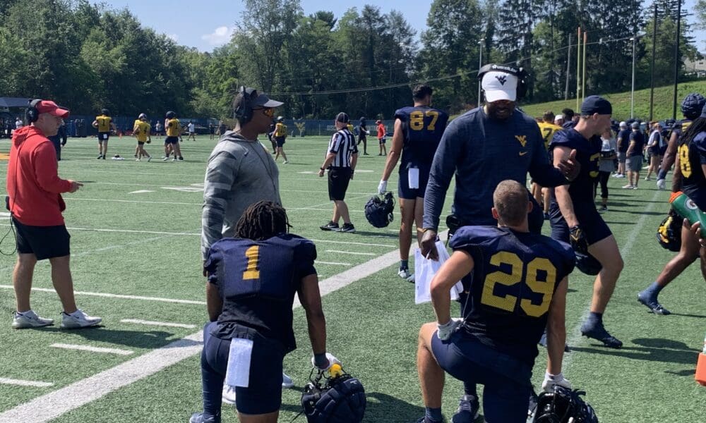 WVU Football OC Chad Scott and WR coach Bilal Marshall talking to Jahiem White and Preston Fox
