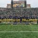 Notre Dame players and coaches on field