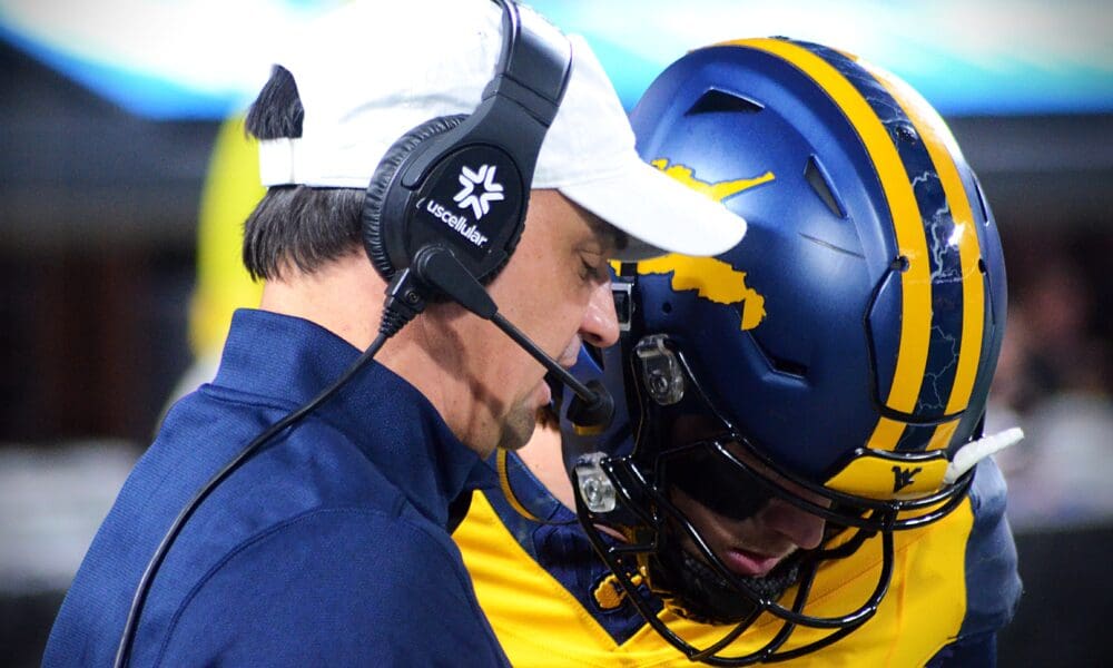 WVU quarterback Garrett Greene talks to head coach Neal Brown before taking the field against UNC in the Duke's Mayo Bowl at Bank of America Stadium in Charlotte, N.C. on Dec. 27, 2023. (Mitchell Northam / WV Sports Now)