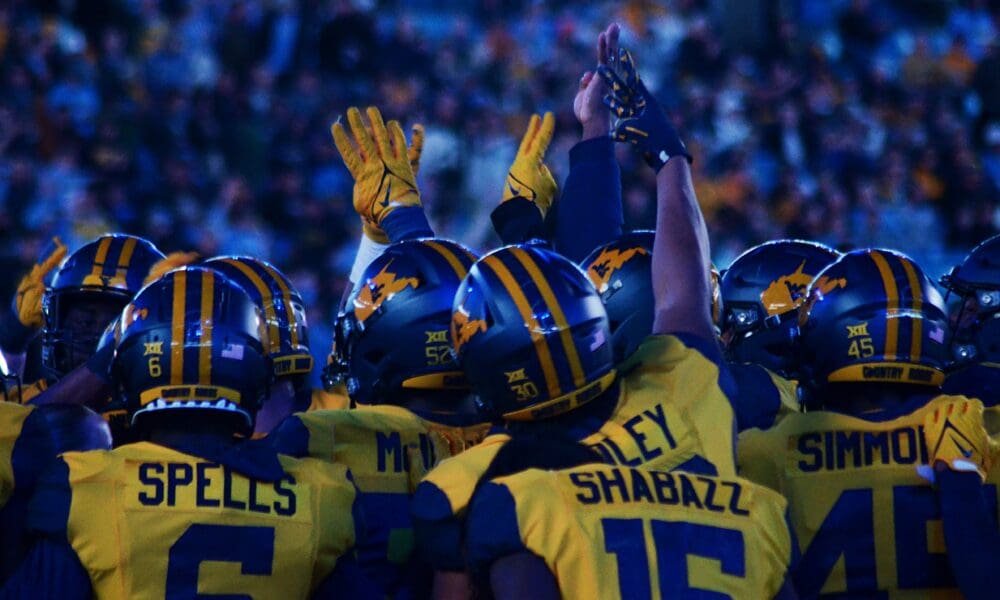 WVU Football players huddle up before the fourth quarter against UNC at the Duke's Mayo Bowl on Dec. 27, 2023, at Bank of America Stadium in Charlotte, N.C. (Mitchell Northam / WV Sports Now)